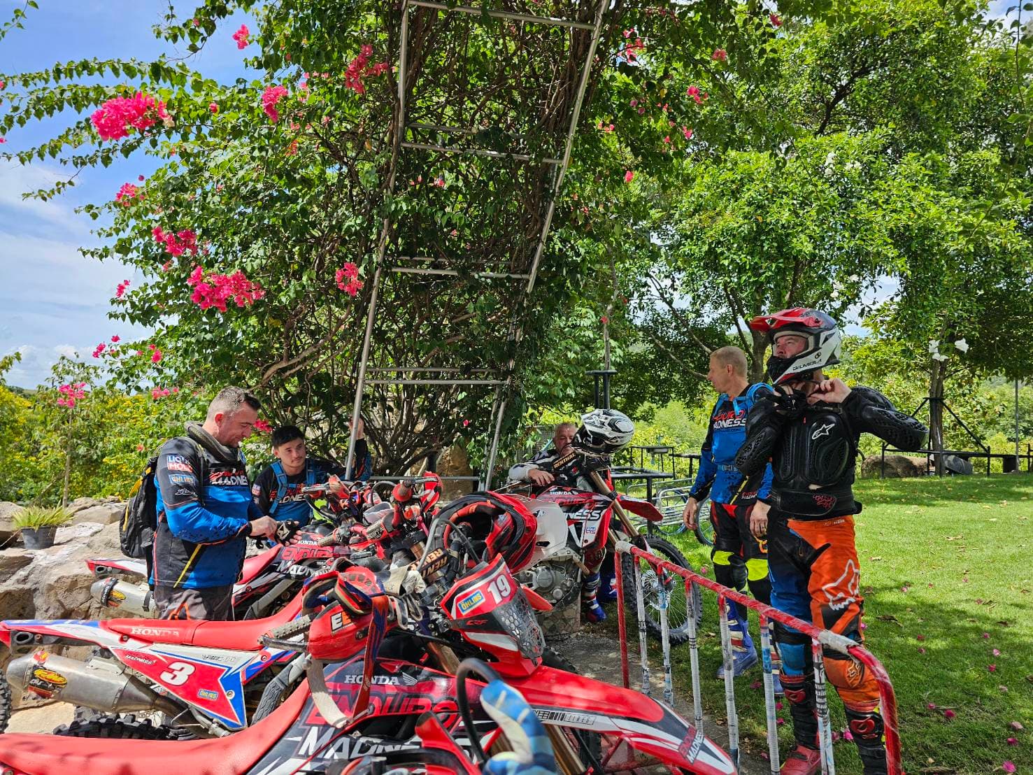 Fleet of dirtbikes lined up at base with riders gearing up