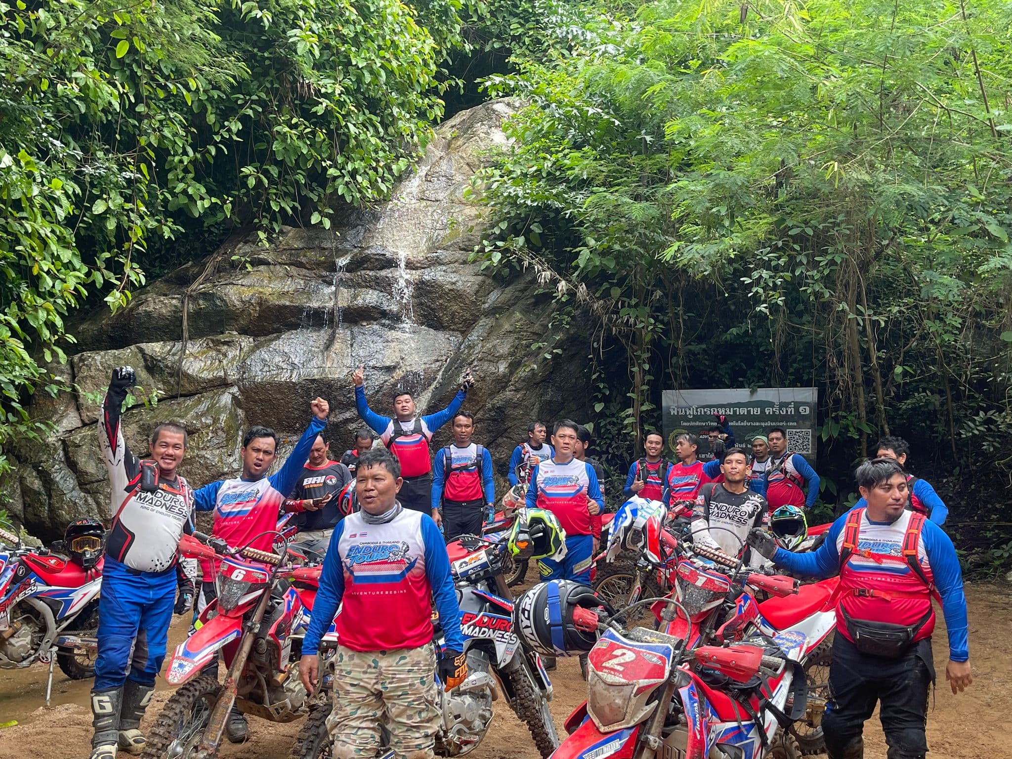 Enduro group celebrating at jungle waterfall in Thailand